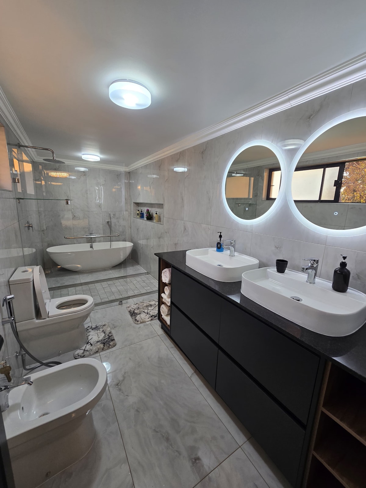 Large ensuite bathroom with double vanity, bidet shower and bathtub.