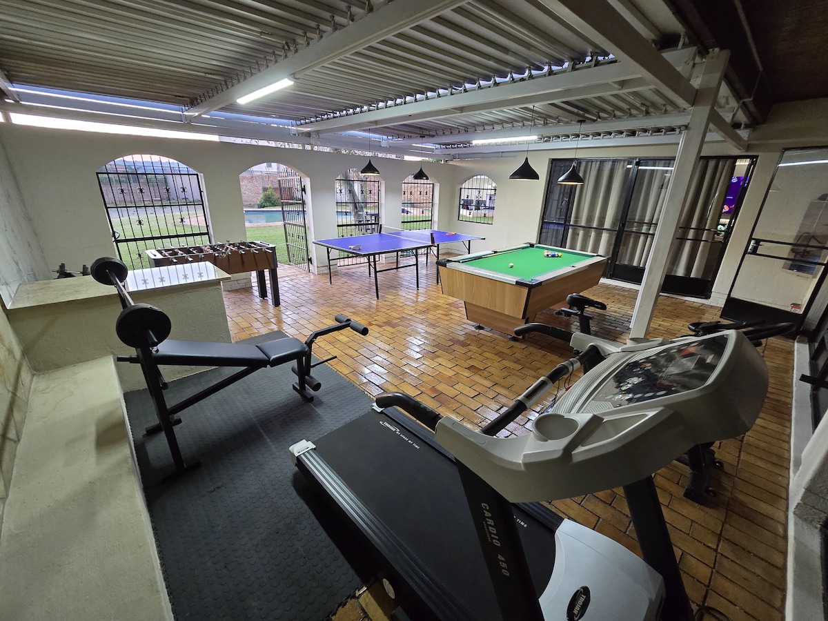 Entertainment area with pool table, table tennis table, foosball, and gym equipment with weights, cycling machine and treadmill