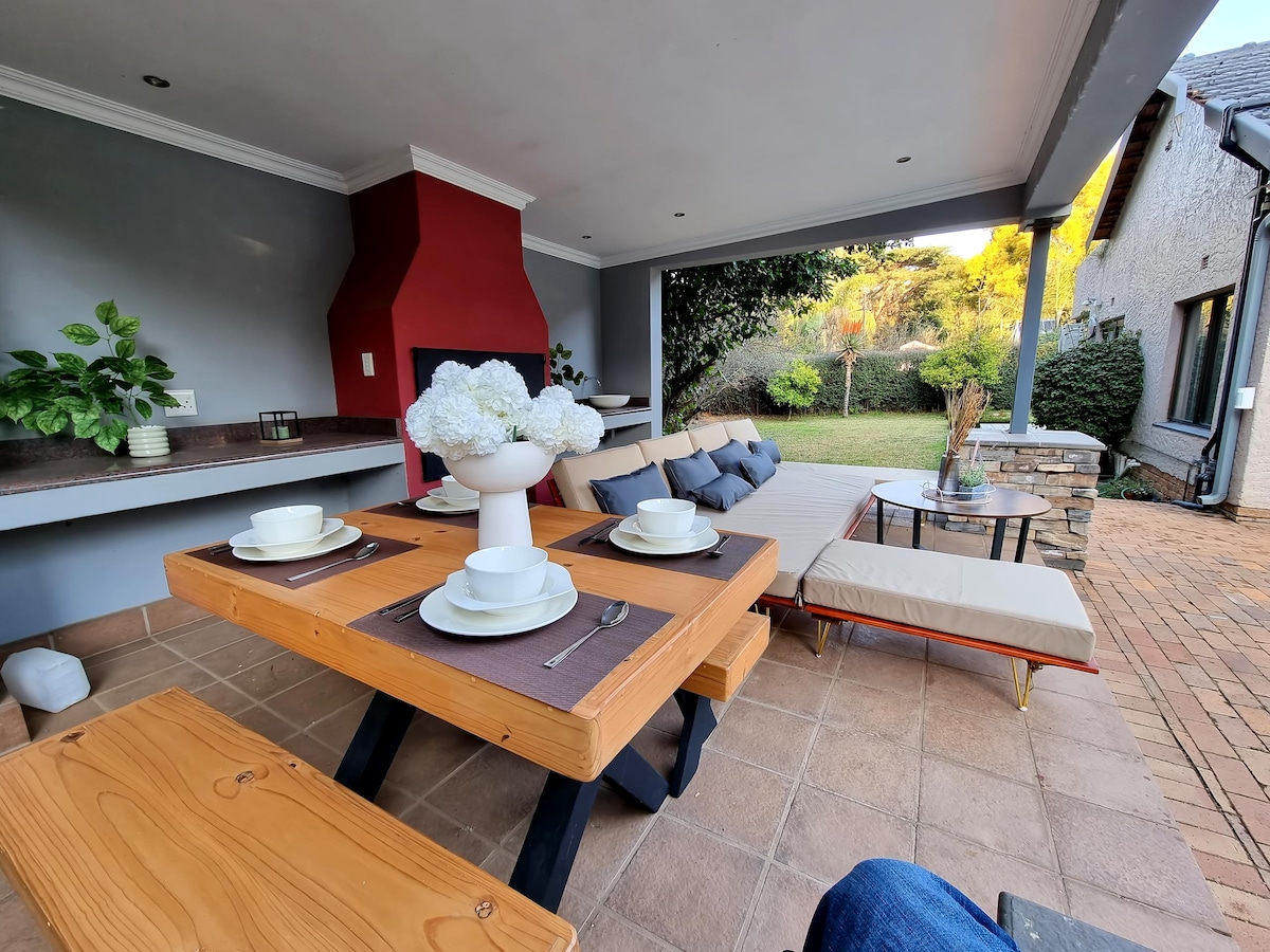 Covered patio area with BBQ/Braai oven, dining table and L-shaped couch