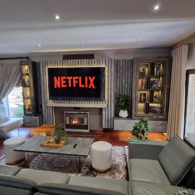 Living room with gas powered fireplace with LED lit media wall and 75` smart TV with Netflix. TV and media wall plugs is fed from solar powered battery inverter.