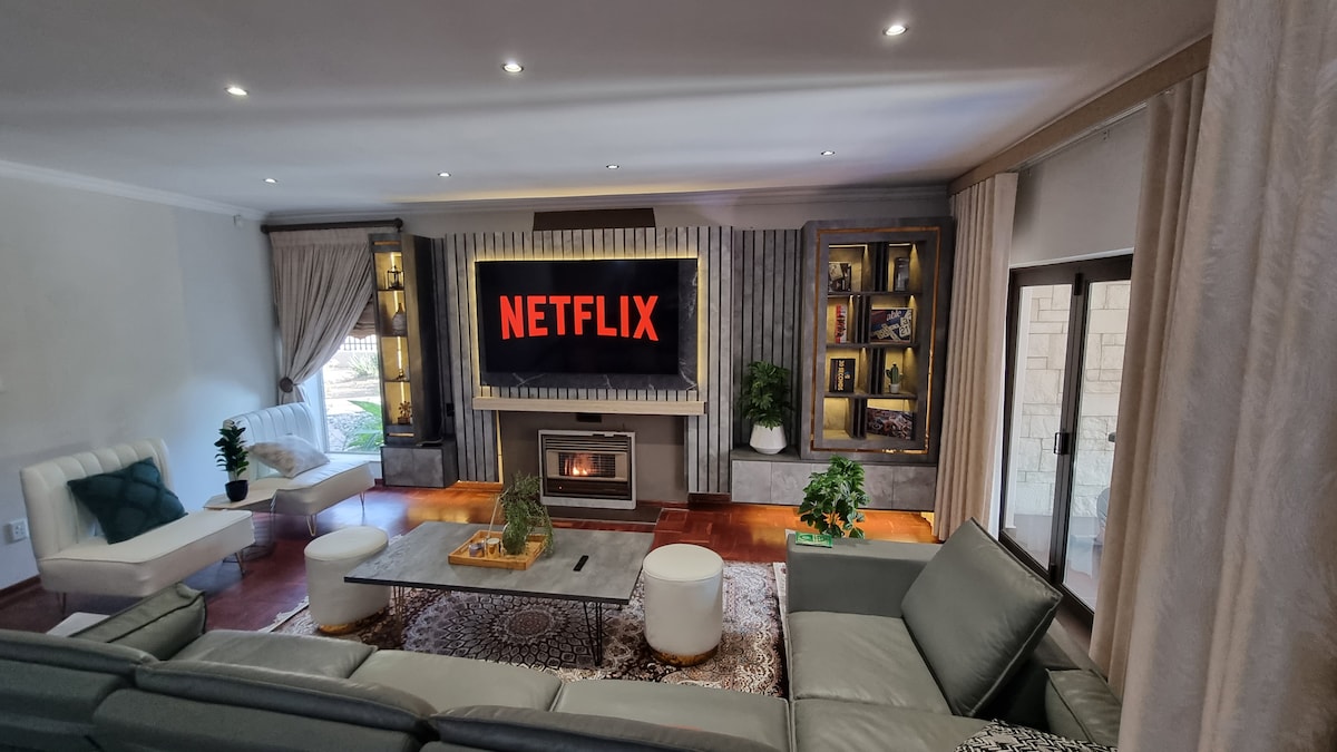 Living room with gas powered fireplace with LED lit media wall and 75` smart TV with Netflix. TV and media wall plugs is fed from solar powered battery inverter.