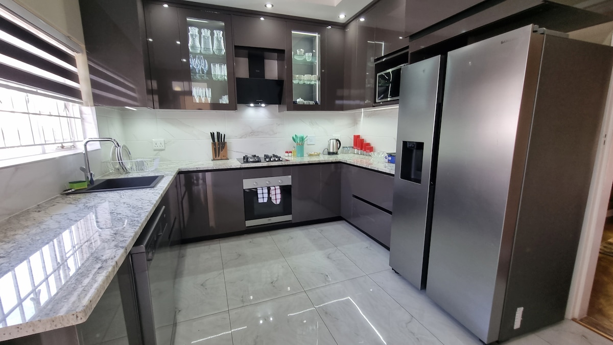Fully stocked modern kitchen with gas stove and oven, dishwasher, microwave and side by side cabinet fridge.